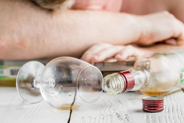 Мужчина лежит на столе среди бокалов и бутылок